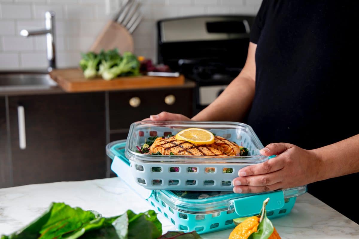 Person holding a container with grilled food ready for refrigeration