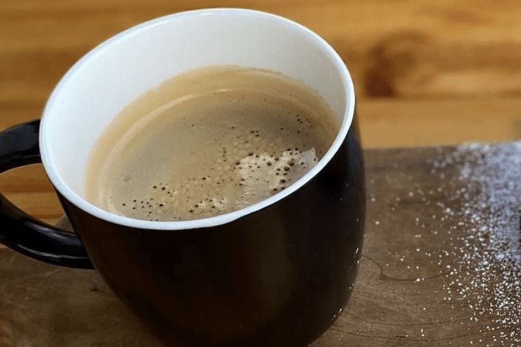 A black cup of freshly brewed espresso with frothy bubbles on top.