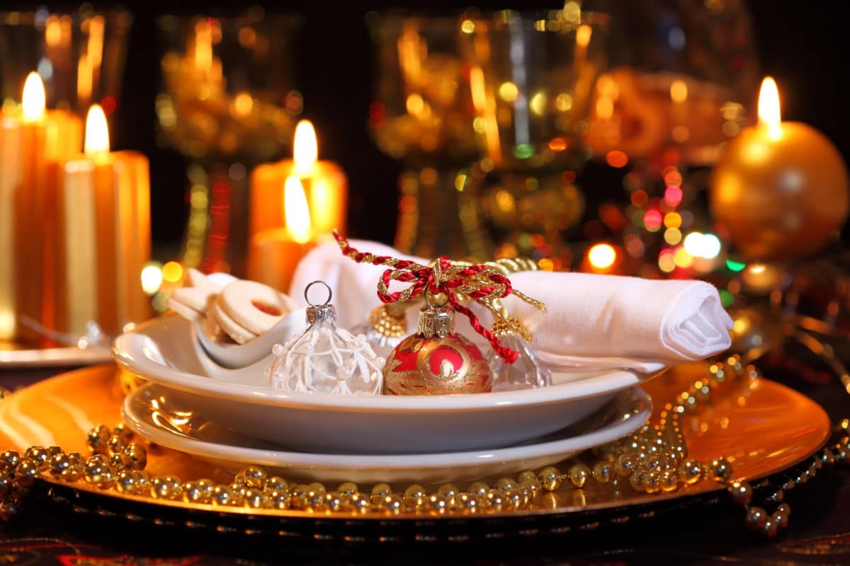Elegant Christmas table setting with candles, ornaments, and gold accents.