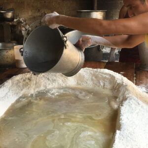 Hand pouring boiling water into a crater formed in a pile of flour.