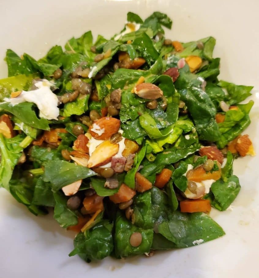 Close-up of a colorful French lentil salad in a white bowl.