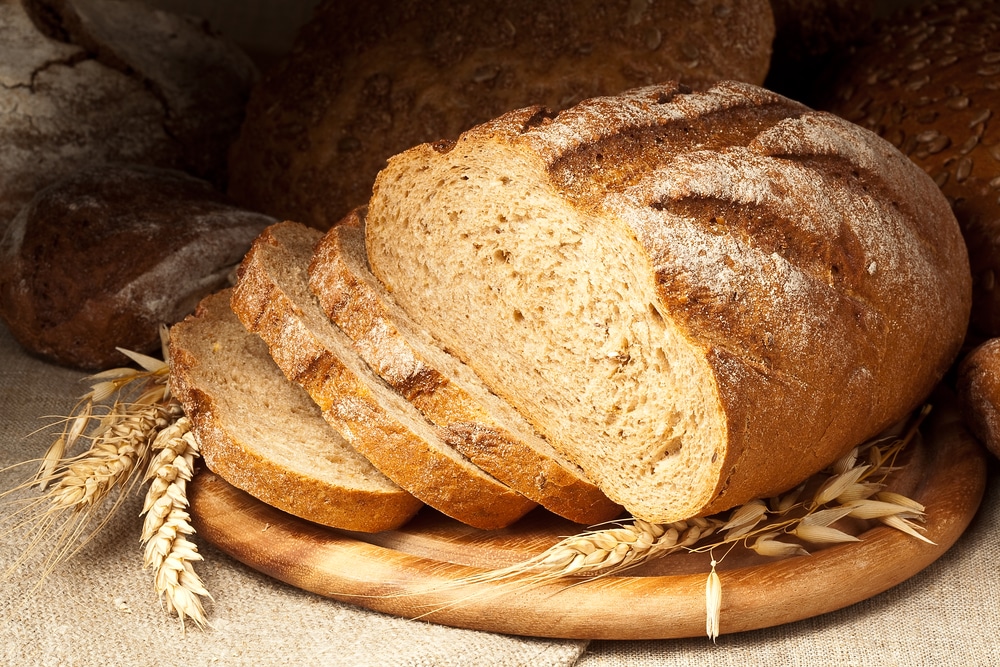 Sliced whole wheat sourdough bread on a wooden board.