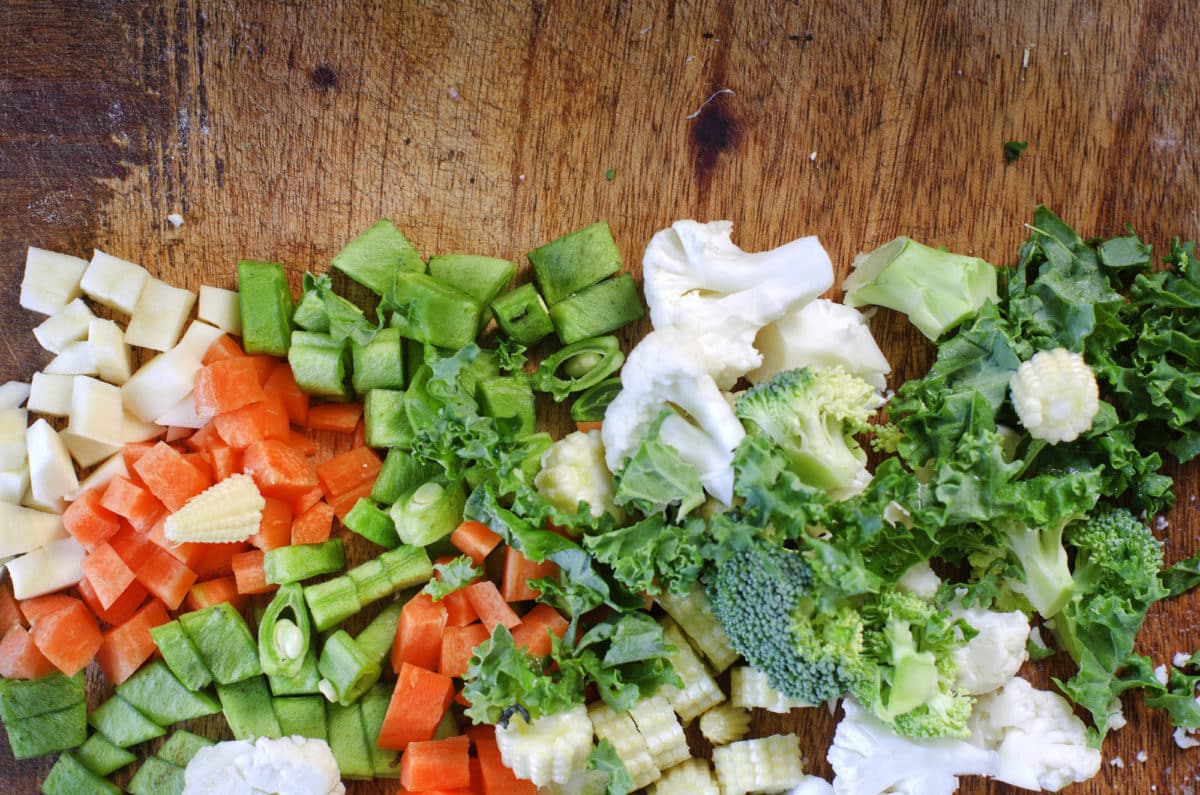 Assorted freshly chopped vegetables on a wooden surface.
