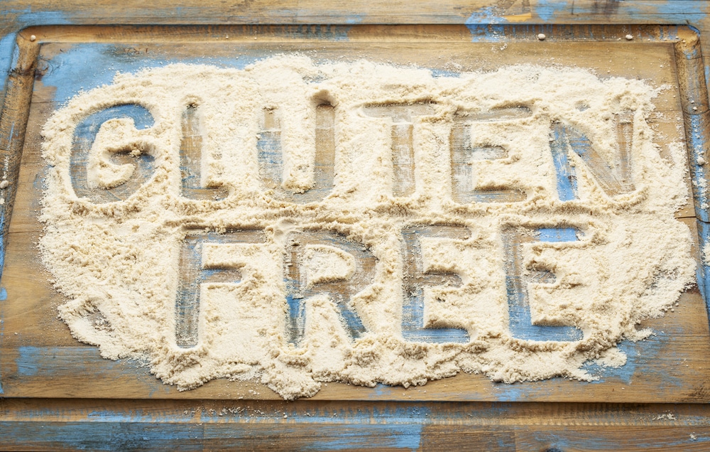Words "Gluten Free" etched in coconut flour on a rustic wooden board.