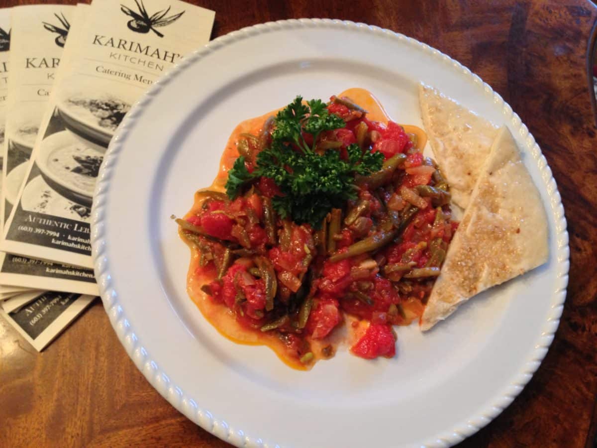 A plated gourmet dish with vibrant vegetables and a side of flatbread.