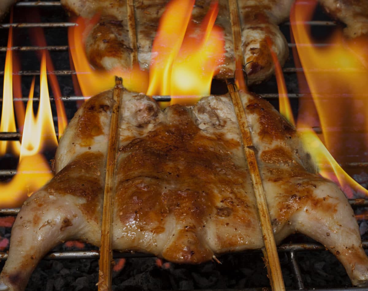 Close-up view of grilled chicken with flames beneath