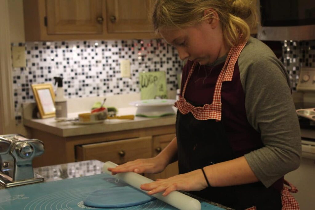 Young girl with her hands on a kitchen countertop.