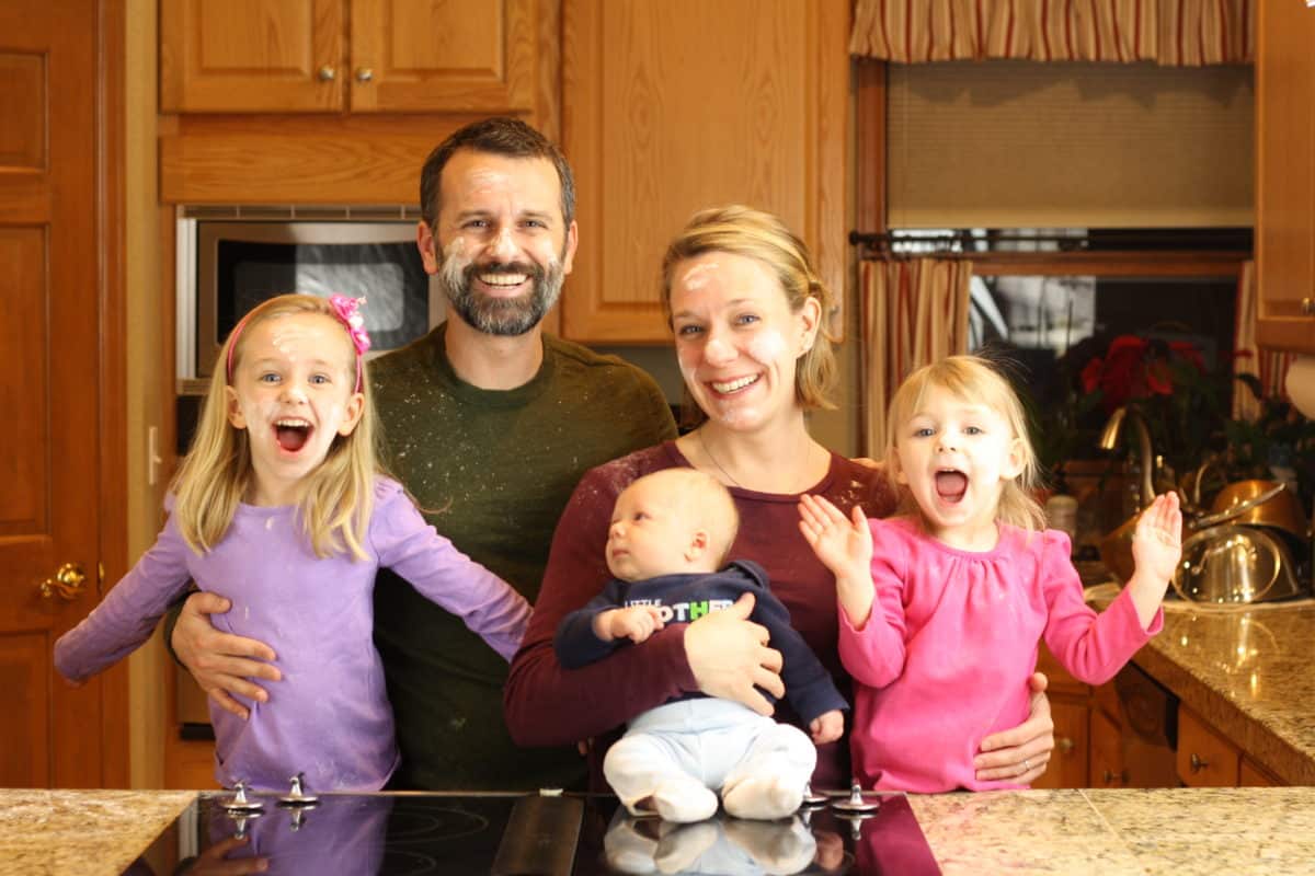 A cheerful family portrait featuring two adults and three young children.