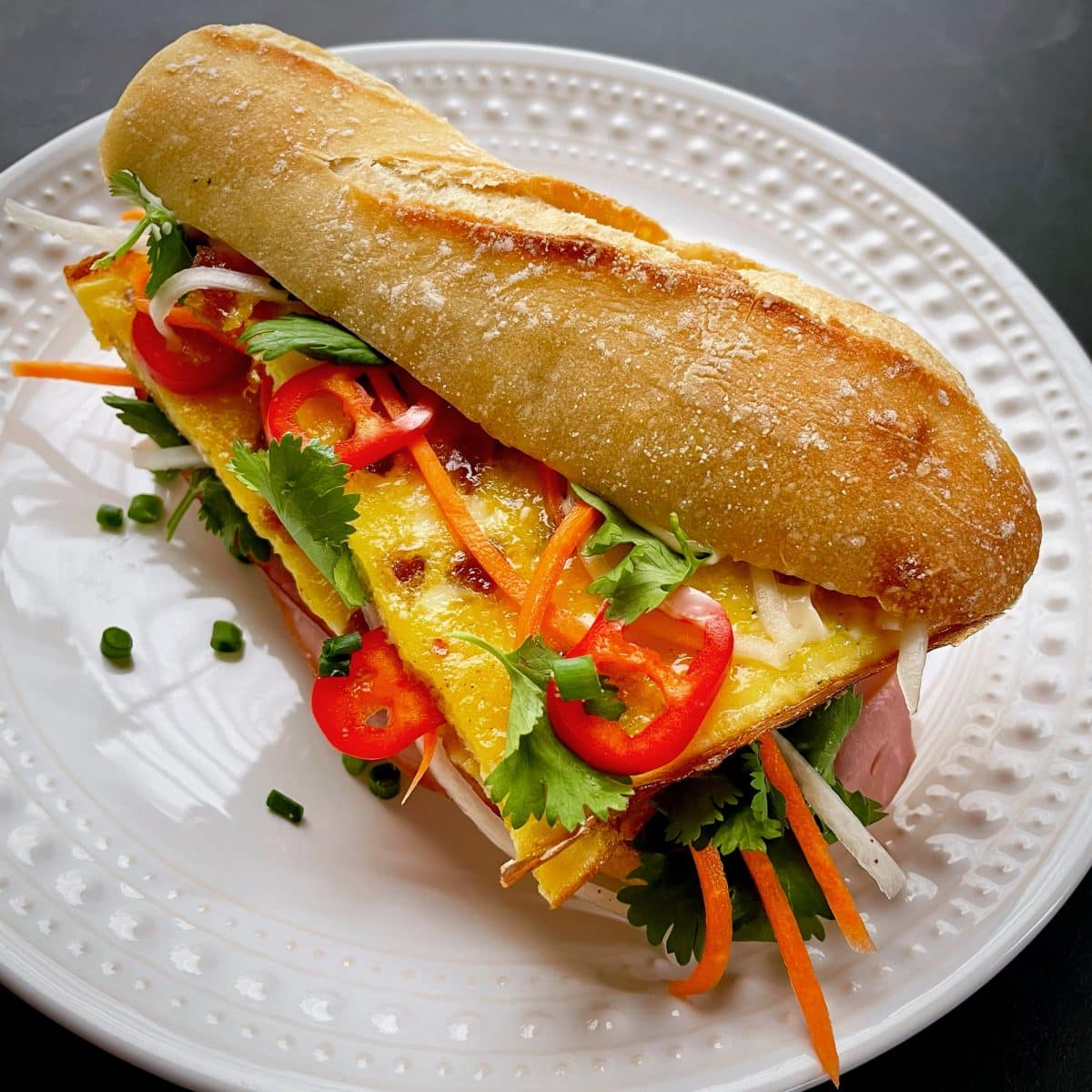 Vietnamese breakfast Bánh Mì sandwich with eggs, vegetables, and meat on a crispy baguette