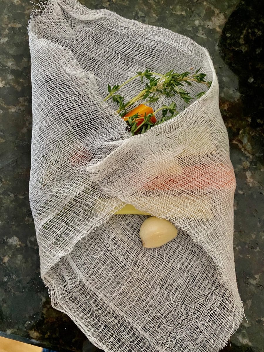 Garlic clove and herbs wrapped in a mesh pouch.