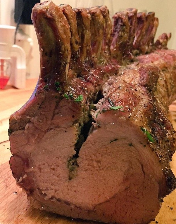 Close-up of roasted pork with rosemary and sage garnish