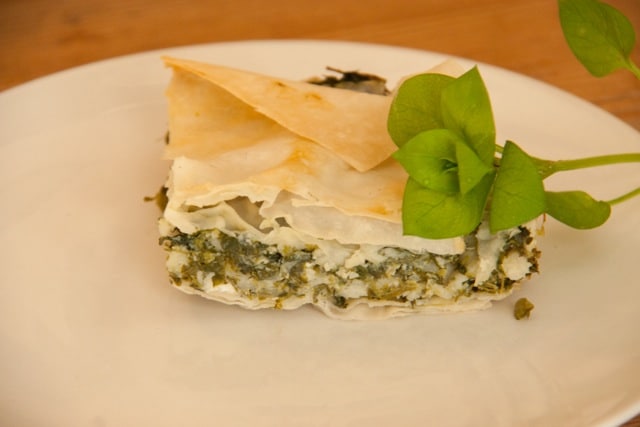 Close-up of hortopita garnished with chickweed on a white plate.