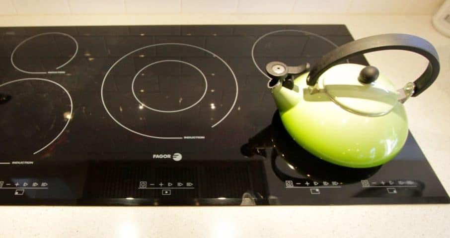 Induction cooktop with a green kettle placed on it.