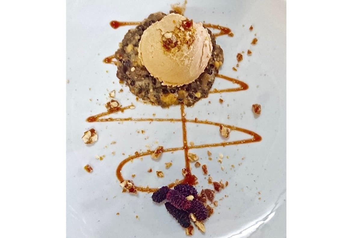Gourmet ice cream dish on a white plate with various toppings.