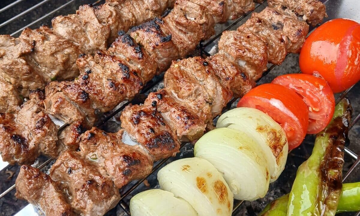saffron kabobs on a grill with onions an tomatoes
