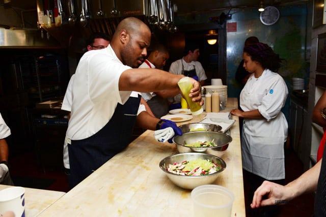 Chefs and cooks diligently preparing dishes in a professional kitchen setting.