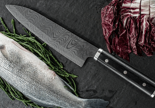 A sleek Kyocera ceramic knife displayed alongside fresh fish and green asparagus