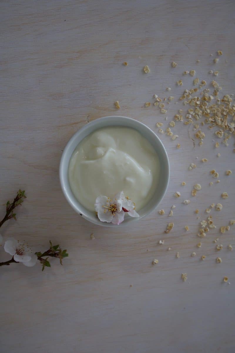 Bowl of labne topped with petals and sprinkled with grains.