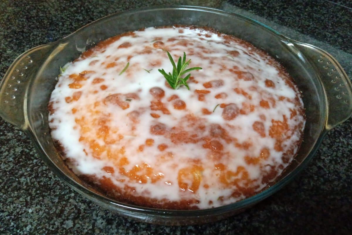 Creamy rosemary-infused lemon sponge cake in a glass dish.
