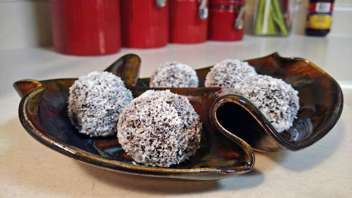 Close-up view of round sweets coated with coconut shavings, served on a decorative plate