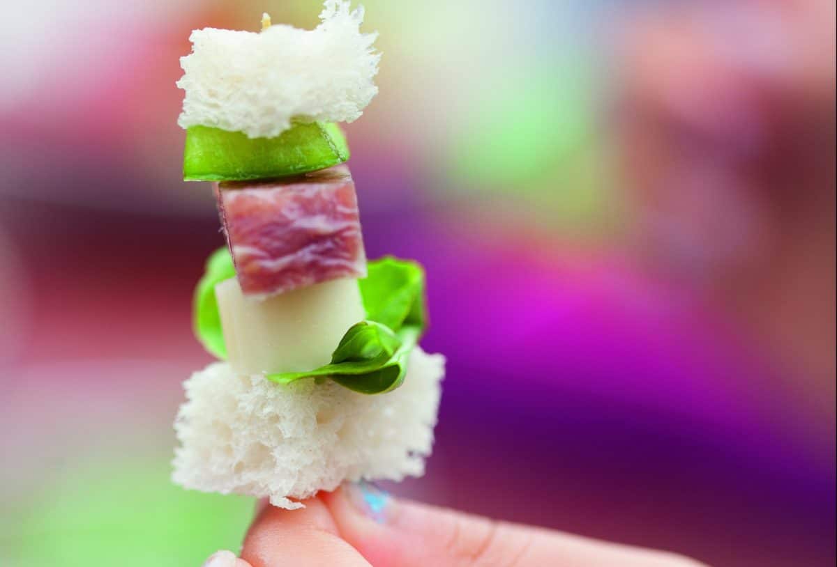 A skewer with sandwich ingredients including bread, cheese, lettuce, and ham.
