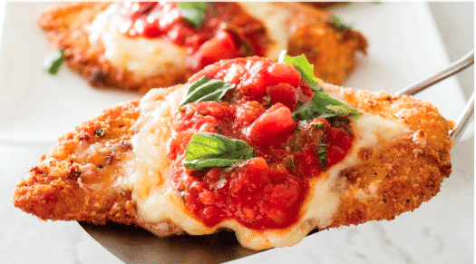 Close-up of a cheesy dish topped with tomatoes and basil