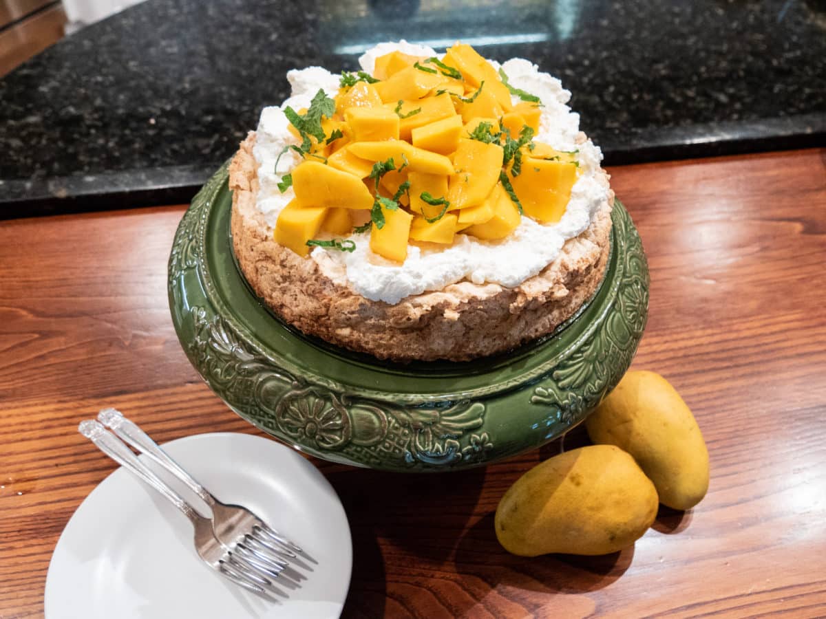 Mango macaroon torte adorned with mango pieces on a green stand