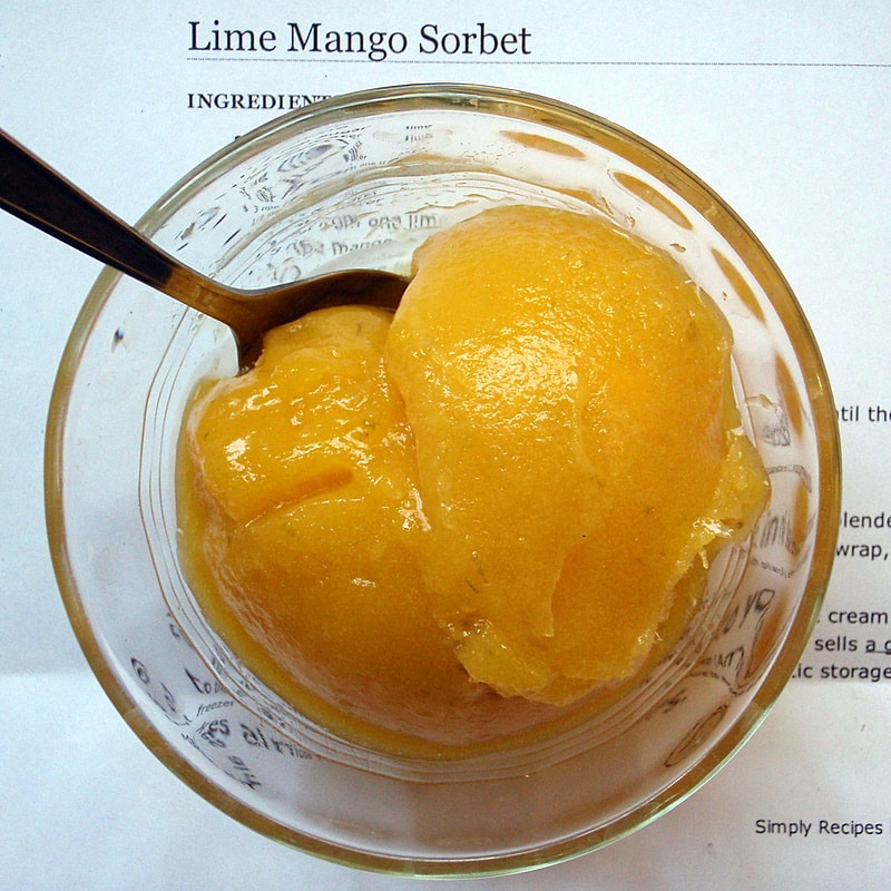Close-up of mango sorbet in a glass bowl with a spoon