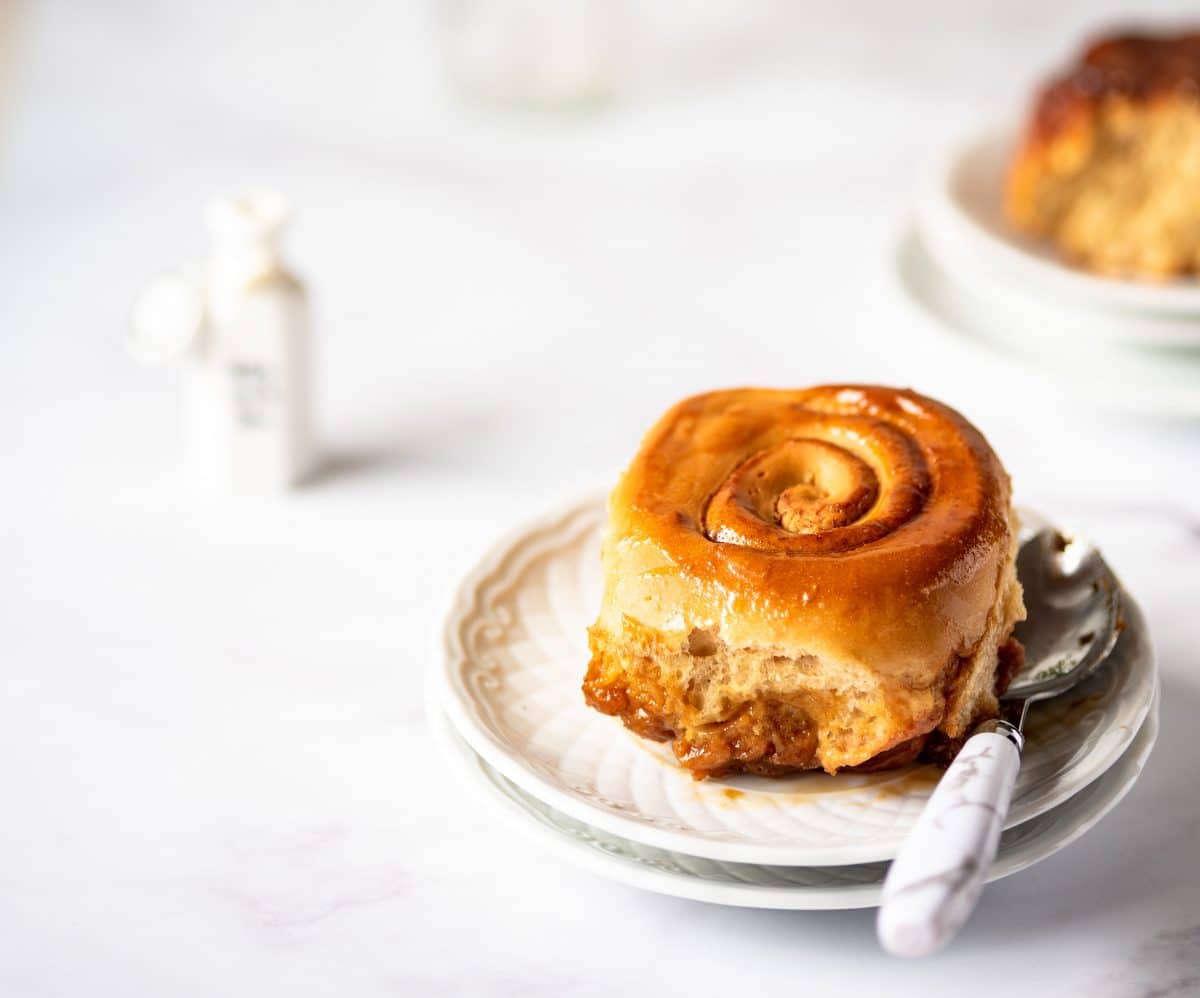 Close-up of a maple-cinnamon roll with a bite taken out, showing its gooey center.