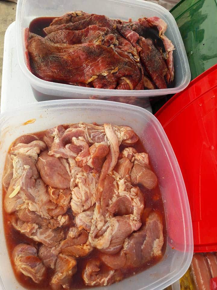 Raw meat pieces marinating in a plastic container.