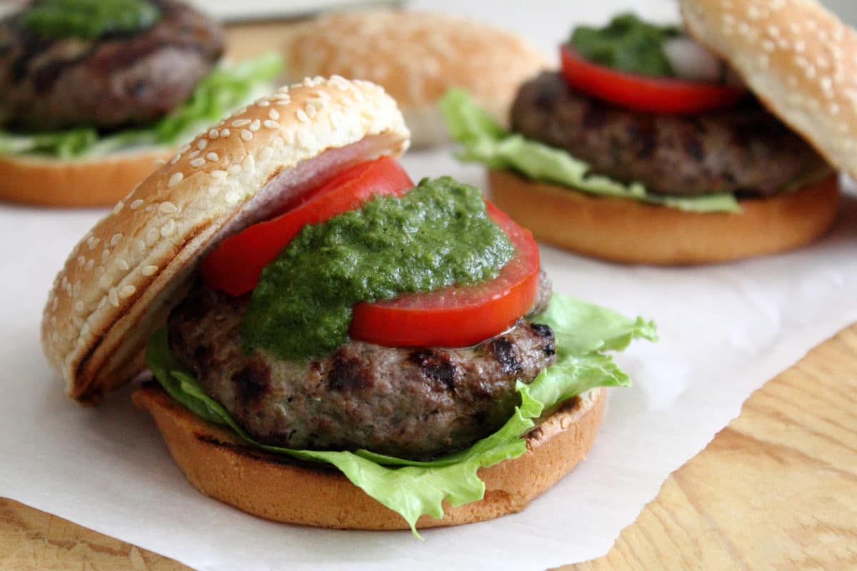 Grilled masala burger with lettuce, tomato, and cilantro-mint chutney between a sesame seed bun.