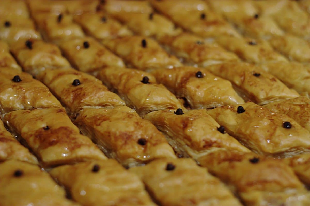 Golden baked dessert with black toppings arranged in rows.