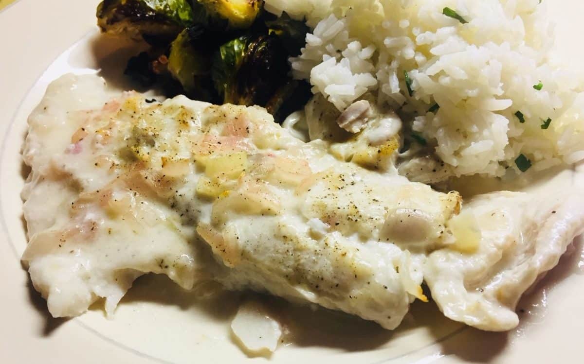 Plated dish with baked fish, fluffy rice, and roasted brussel sprouts.