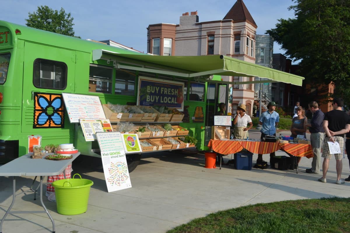 Green bus displaying "Buy Fresh Buy Local" offering fresh produce.