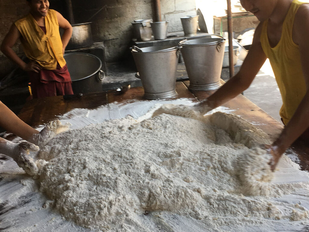 Two young individuals shaping dough on a wooden surface.