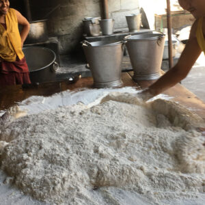 Two young individuals shaping dough on a wooden surface.