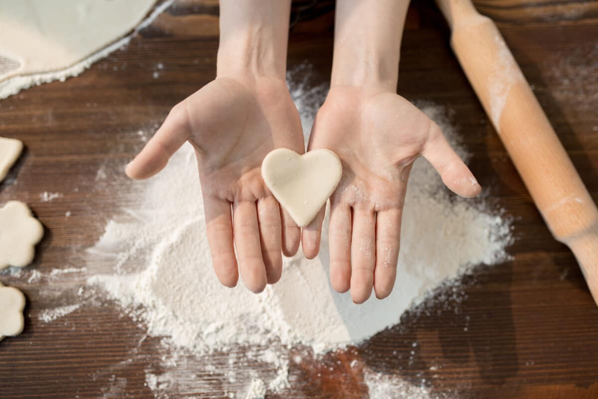 hands cutting a heart of flour