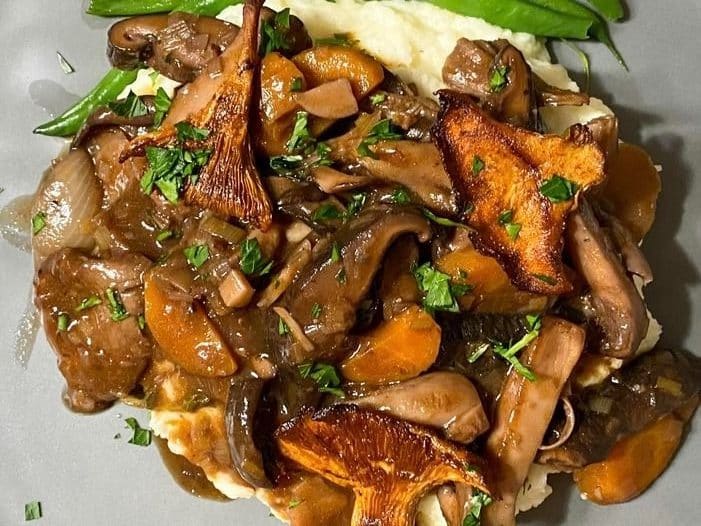 Close-up of mushroom bourguignon with green garnish.