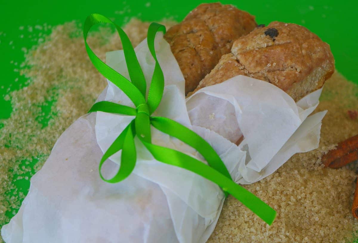 A pair of orange coconut leadpipe pastries wrapped in paper and tied with a green ribbon.