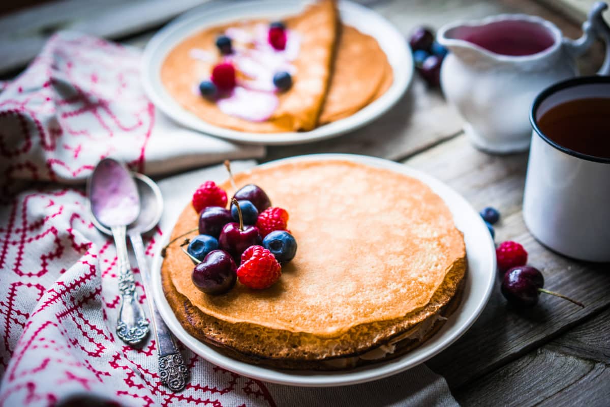 Stack of pancakes topped with fresh berries on a wooden table.