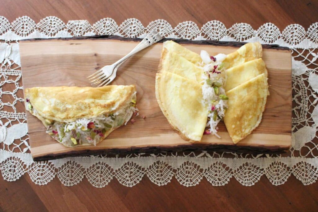 Split crepes revealing fresh filling, set on a wooden board with a lace backdrop.