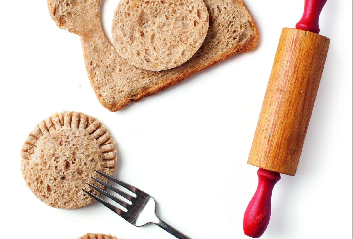 Rolling pin, fork, and freshly made sandwich pockets on a board.