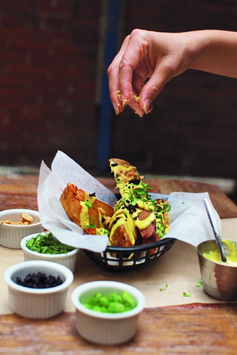 Hand adding salt to Peruvian fries in an artistic presentation