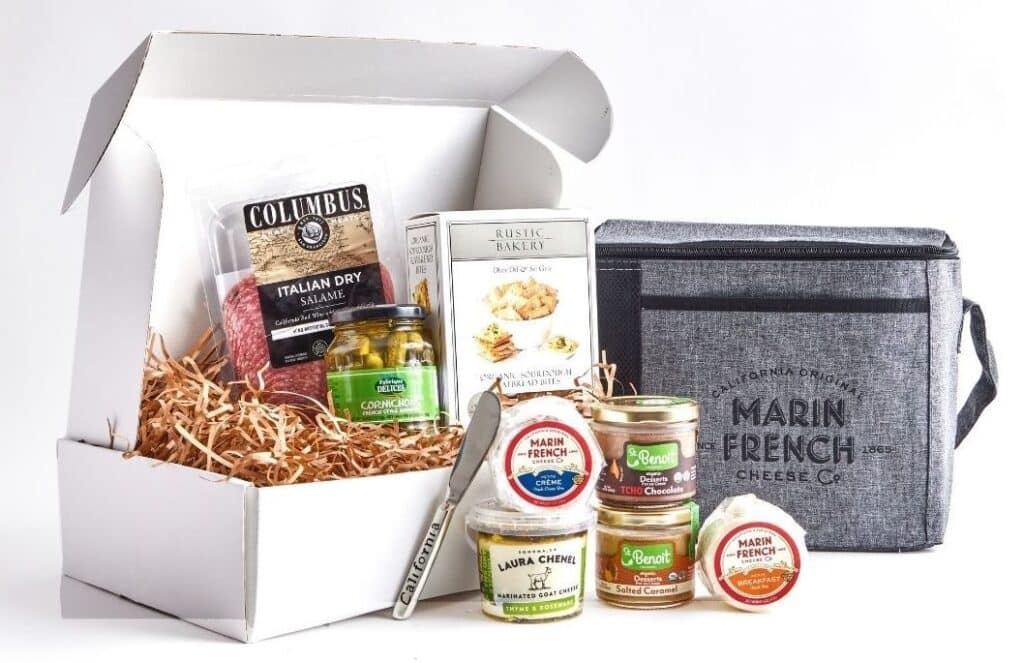 A boxed assortment of cheeses, crackers, and accompaniments for a picnic.