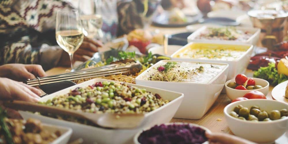 People gathering around a potluck spread with various dishes.