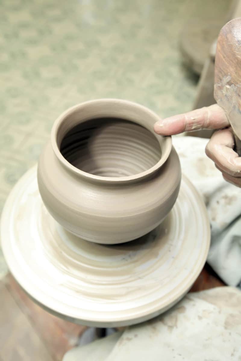 Close-up of hands skillfully shaping a clay pot on a pottery wheel.