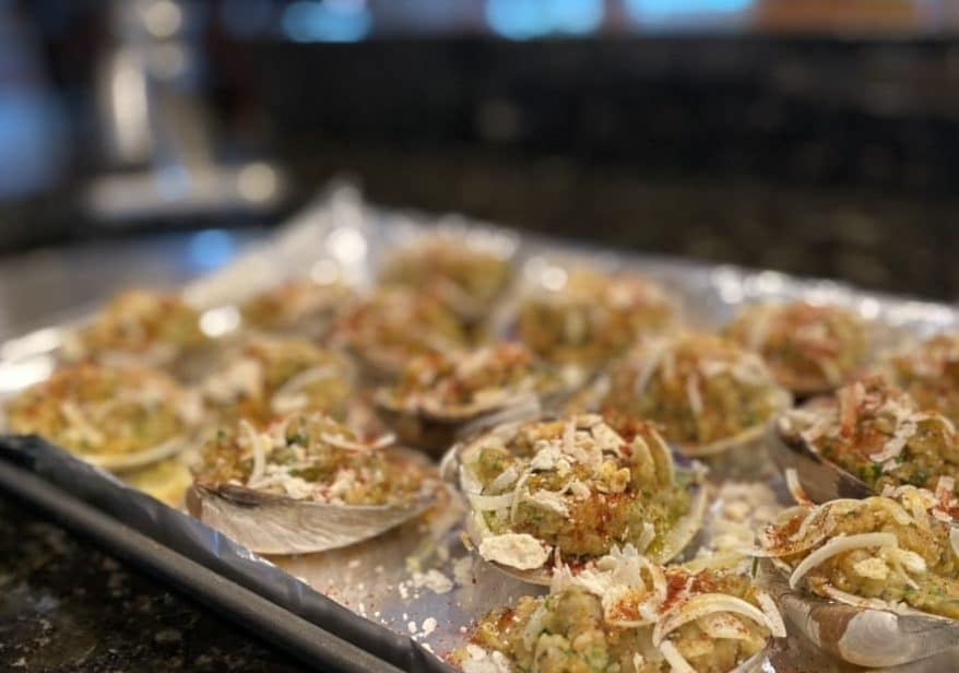 Clam shells filled with stuffing mix, arranged on a baking tray, ready for oven.