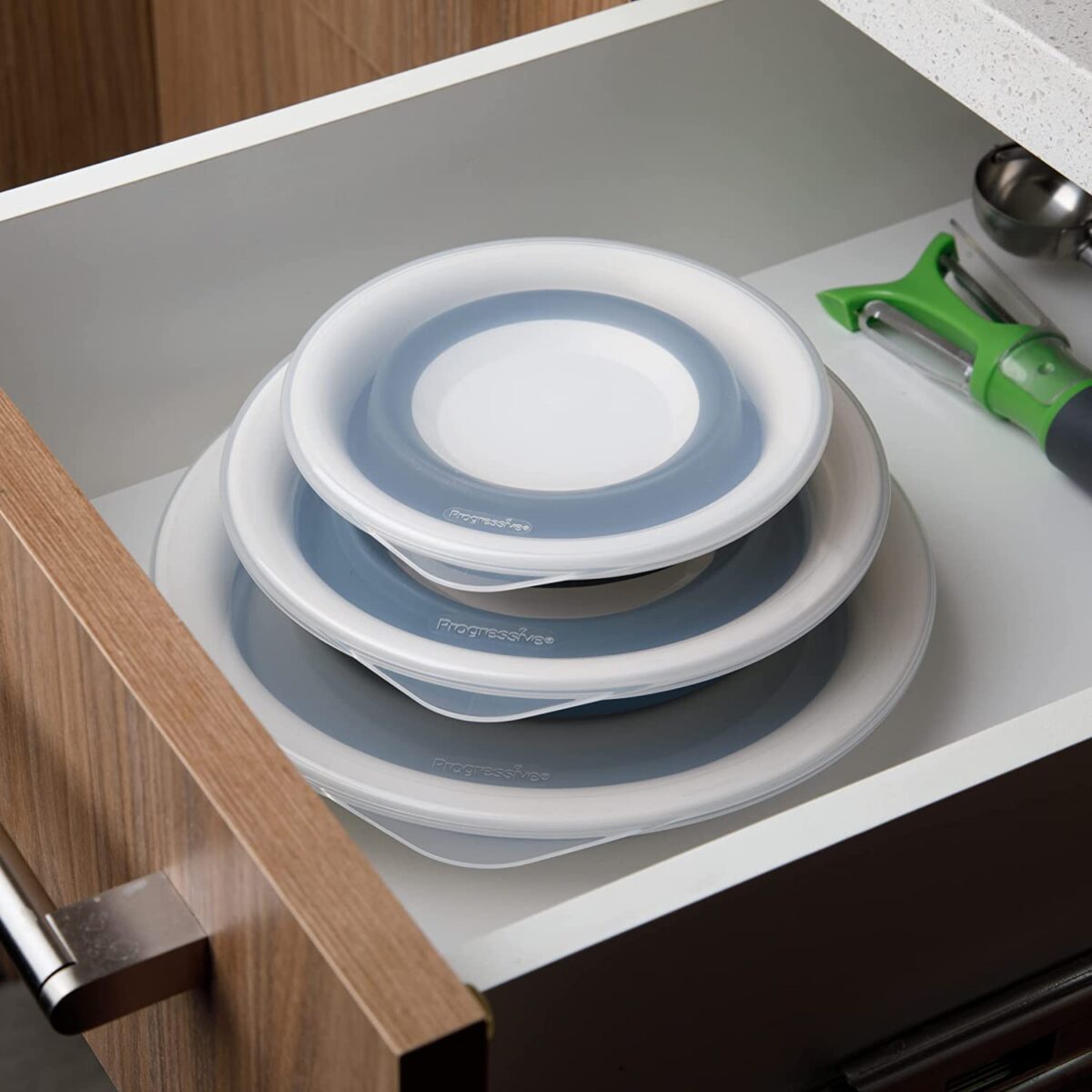 A set of Progressive International collapsible storage bowls with a kitchen tool beside them.