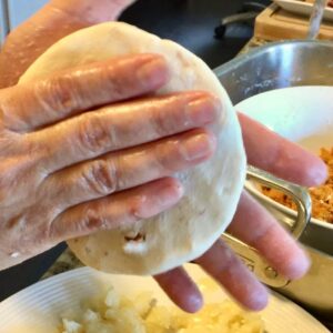Hand sealing and flattening a pupusa before grilling