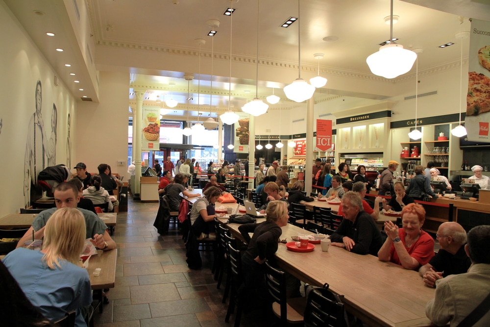 Interior view of a bustling restaurant in Quebec City with patrons seated and chatting.